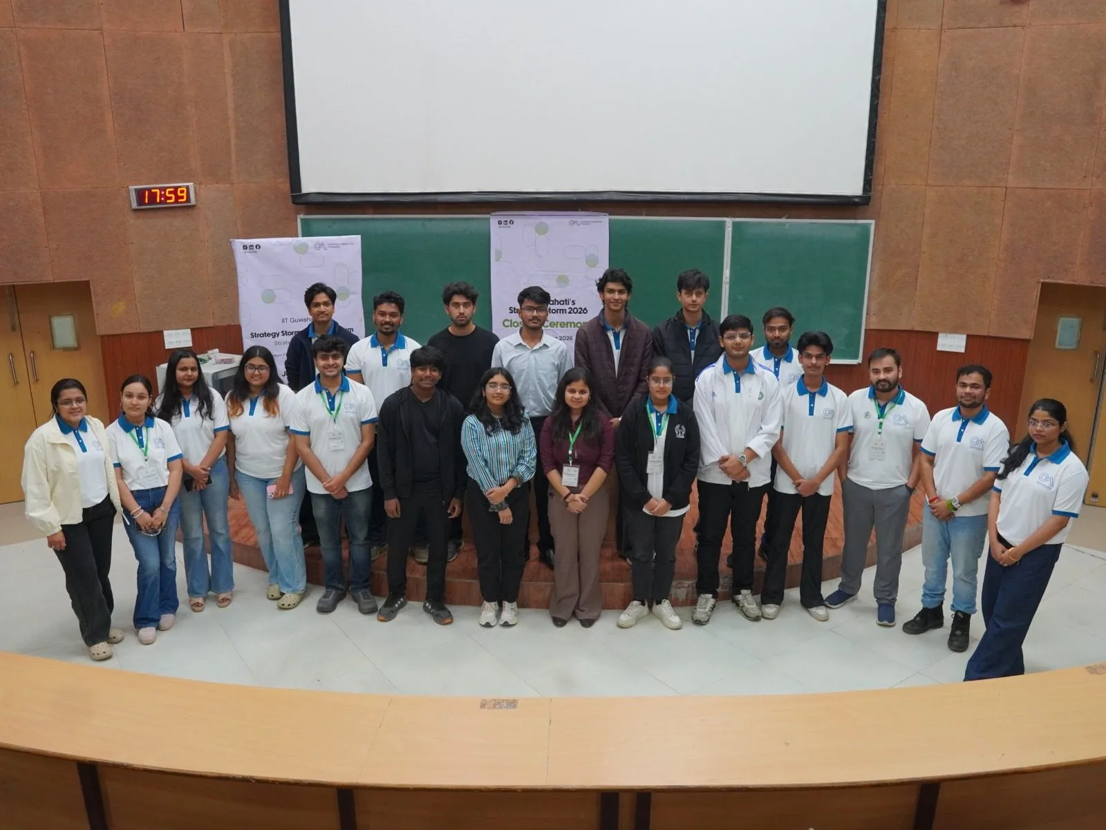 Consulting and Analytics Club IIT Guwahati group photo in matching white polo tees with blue accents at an event